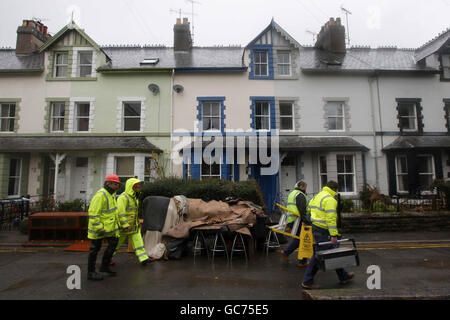 Los obreros limpian parte del centro de la ciudad de Cockermouth después de las recientes inundaciones. Foto de stock