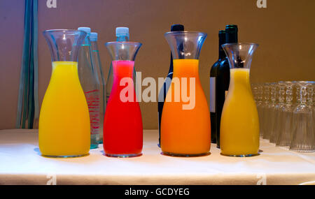 Jarras de jugo fresco de naranja, limón, piña, melocotón, albaricoque, angulares, papaya descansando sobre una mesa para una fiesta Foto de stock