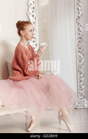 Guapa joven bailarina bebedores de té. En bailarina tutu y suéter rosa Foto de stock