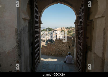 Hombre sentado en un complejo gateway de Kumbhalgarh Fort, Rajasthan, India Foto de stock