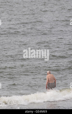 Mantenerse en forma en la vida posterior: senior masculino adulto viejo hombre de pie en el mar cerca para ir a nadar, UK Foto de stock