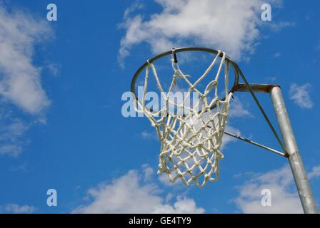 Perspectiva abstracta de un aro de baloncesto con net contra un cielo azul y la nube de fondo. Foto de stock