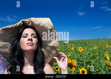 Bastante joven morenita mujer vistiendo gran sombrero en un campo de girasol.