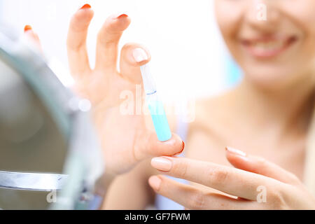Esteticistas mano muestra una ampolla con un preparado cosmético Foto de stock