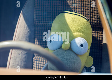 Homer Simpson soft toy doll detrás del volante de un coche Foto de stock