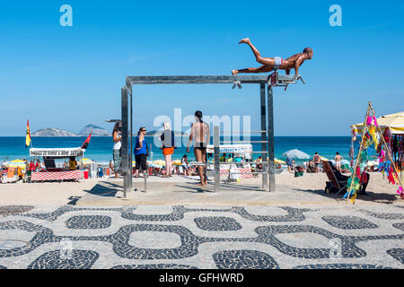Río de Janeiro, Brasil - Julio 24, 2016: el joven en una de las muchas estaciones de ejercicios al aire libre en la playa de Ipanema. Foto de stock
