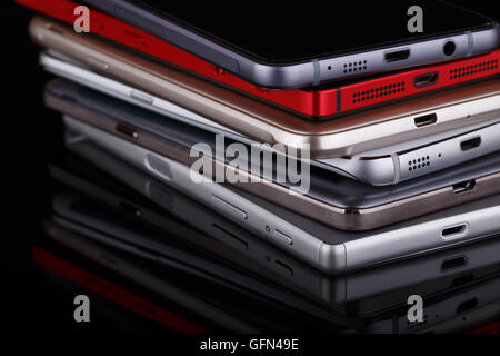 Montón de dispositivos electrónicos cercanos - smartphones sobre fondo negro Foto de stock