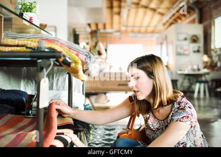 Mujer joven mirando en una tienda de alfombras en un estante