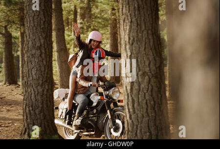 Exuberante mujer joven montando en motocicleta woods Foto de stock