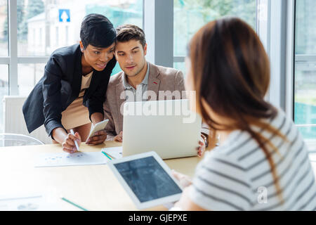 El grupo de empresarios que trabajan con ordenador portátil, tablet y teléfono celular en la reunión de negocios
