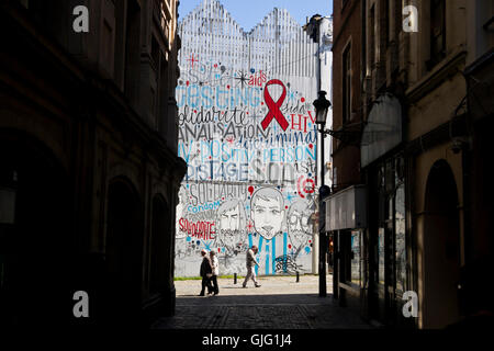 Los peatones atravesar una pared graffitied en Bruselas, Bélgica