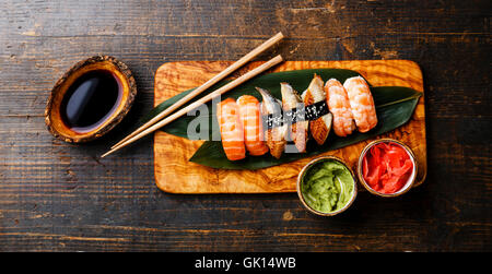 Nigiri Sushi Conjunto de hojas verdes de bambú en Olive wood board con salsa de soja sobre fondo de madera