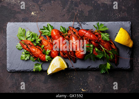 Rojo de langostinos cocidos con limón en piedra pizarra sobre fondo oscuro Foto de stock