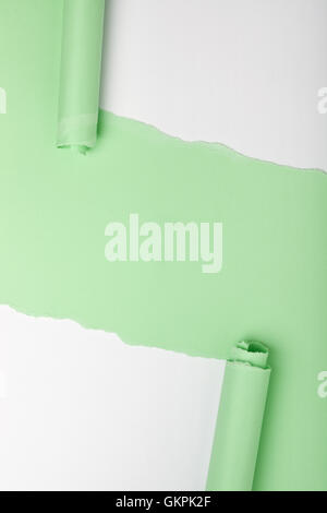 Las lágrimas en un pedazo de papel verde revelando fondo blanco debajo
