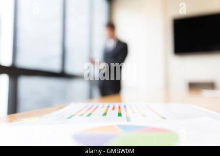 Informe de gráfico de análisis de negocios con antecedentes del empresario en traje de pie junto a la ventana de la oficina Foto de stock