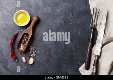 Hierbas y especias. Ingredientes de cocina y utensilios. El ají, el aceite de oliva, sal y pimienta. Vista desde arriba en la tabla de piedra con espacio de copia Foto de stock