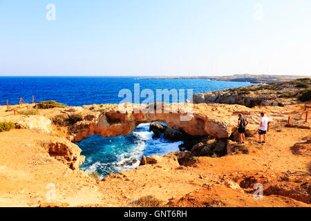 Los turistas admirar el arco de piedra natural, Kamara Toy Koraka, Cabo Greko, Ammohostos, Chipre.