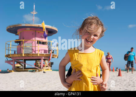 Niña en la playa con su hermano pequeño que se oculta detrás de su
