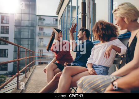 Grupo multirracial de amigos divirtiéndose en balcón y dar de alta 5. Los jóvenes disfrutando en la terraza.
