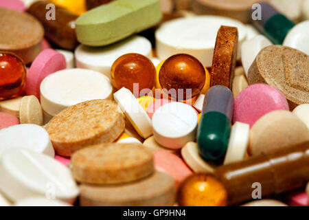 Colores surtidos de píldoras y cápsulas sobre fondo blanco de cerca, horizontal, el enfoque selectivo, concepto médico Foto de stock