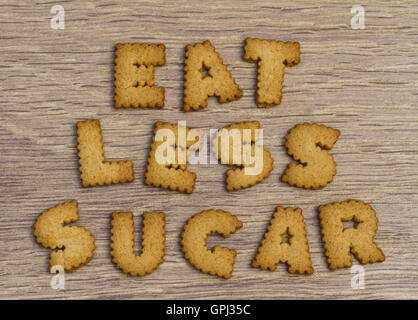Asesoramiento Alimentario enunciadas con el alfabeto en forma de cookies indicando a comer menos azúcar y sobre un fondo de madera. Foto de stock