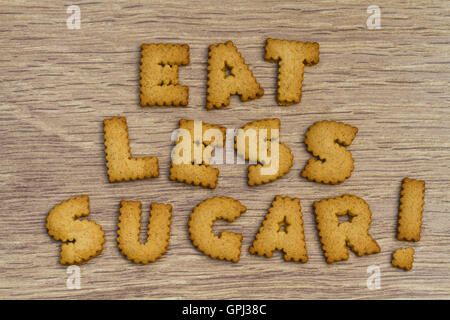 Asesoramiento Alimentario enunciadas con el alfabeto en forma de cookies indicando a comer menos azúcar y sobre un fondo de madera. Foto de stock