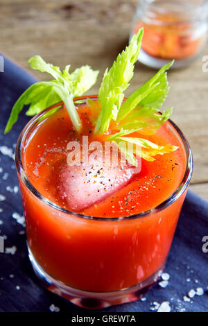 El jugo de tomate con apio, especias, sal y hielo en parte las gafas Foto de stock