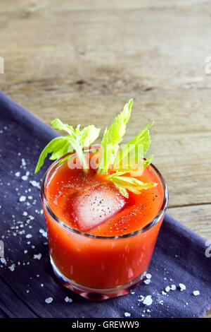 El jugo de tomate con apio, especias, sal y hielo en parte con gafas de espacio de copia Foto de stock