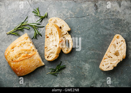 Rebanadas de pan ciabatta y romero en piedra gris de fondo de pizarra