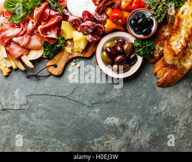 Ingredientes de comida italiana fondo con jamón, salami, queso parmesano, aceitunas, Bread Sticks en piedra pizarra