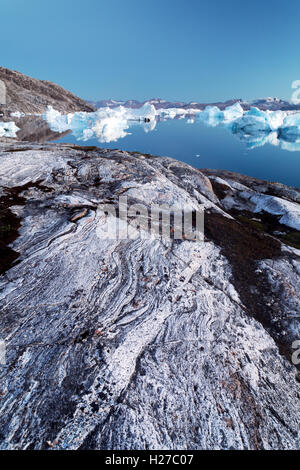 Los icebergs y glaciar de roca pulida al atardecer a lo largo del fiordo Sermilik cerca del asentamiento de Tiniteqilaq, Groenlandia Oriental Foto de stock