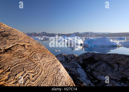 Los icebergs y glaciar de roca pulida al atardecer a lo largo del fiordo Sermilik cerca del asentamiento de Tiniteqilaq, Groenlandia Oriental Foto de stock