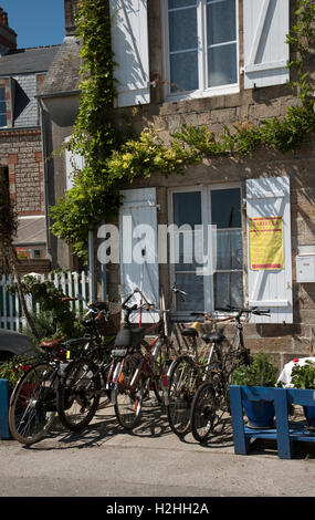 La comuna costera de Barfleur en Normandía, noroeste de Francia. Ciclos turísticos estacionados fuera de una casa de granito con persianas
