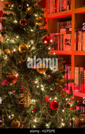 Detalle del árbol de navidad artificial, decorado en tonos rojos y dorados y bella hadita luces centelleantes - casa privada, GB, Reino Unido. Foto de stock
