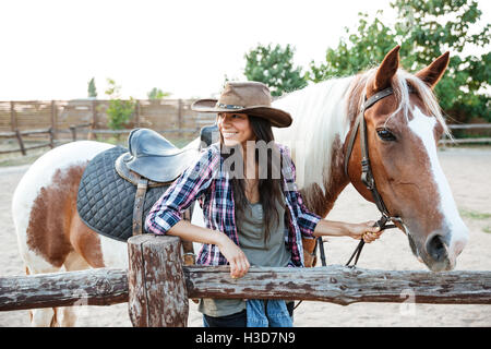 Retrato de mujer joven atractiva feliz cowgirl a caballo en el rancho