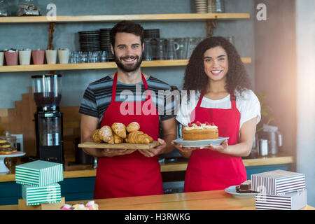 Retrato de camarero y camarera sosteniendo una bandeja de croissants y pasteles Foto de stock