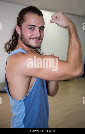 Retrato del hombre sonriente flexionando sus bíceps
