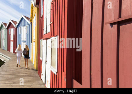 Dos mujeres que caminaban junto a la pesca cabañas, Smögen, Bohuslän, oeste de Suecia, Suecia
