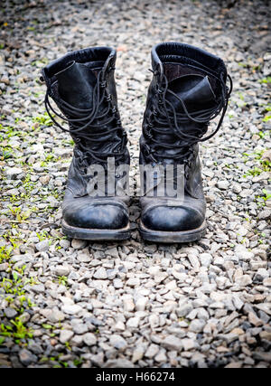 Un par de viejas botas militares sobre la superficie de piedras Foto de stock