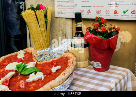Pizza Margherita, spaghetti y frasco de vino de Chianti en una mesa fuera de un restaurante en Roma, Lazio, Italia