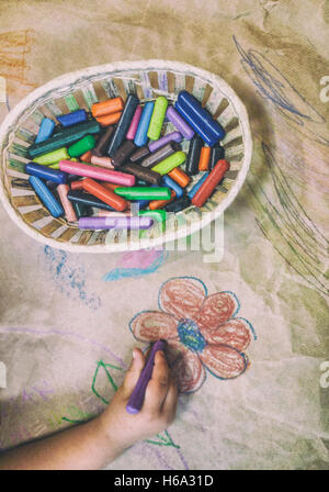 Dibujo infantil con una canasta de lápices de cera sobre la artesanía del papel de embalaje. Un alto ángulo de visualización
