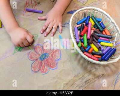 Dibujo infantil con una canasta de lápices de cera sobre la artesanía del papel de embalaje. Un alto ángulo de visualización