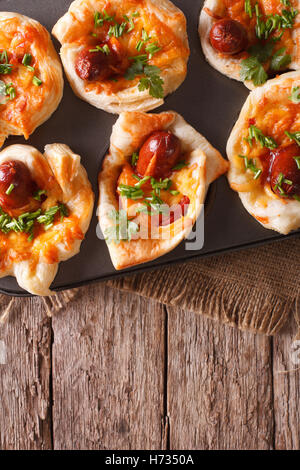 Bollos de hojaldre con salchichas, queso y cebolla en un plato de hornear. vista vertical desde arriba Foto de stock