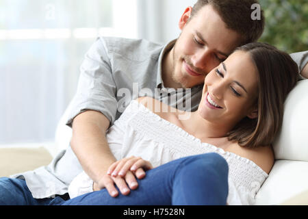 Las manos de afectuosa pareja sentada en un sofá en casa con un ambiente hogareño de fondo. Concepto de amor