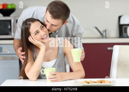 Feliz esposo besar en la mejilla a su esposa en el desayuno. Concepto de la vida matrimonial