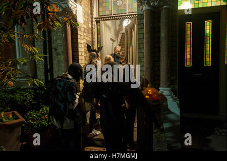 Personas disfrazadas llamando a una puerta en una casa residencial de Londres Foto de stock