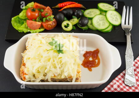 Porción de lasaña con verduras frescas en una placa Foto de stock