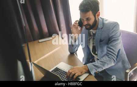 Empresario ocupado trabajando desde casa en portátil y teléfono Foto de stock