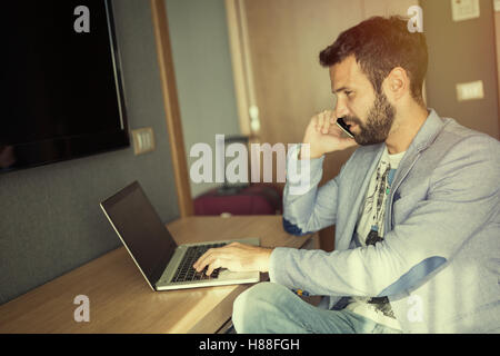 Empresario ocupado trabajando desde casa en portátil y teléfono Foto de stock