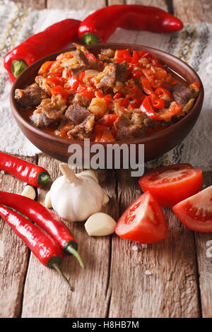 El guiso de cordero con cebolla, tomate y pimiento en un tazón de cerca en la tabla vertical. Foto de stock